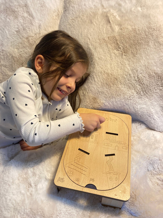 Fillette jouant avec une planche Montessori en bois posée sur un support, souriante et concentrée sur l’activité éducative.