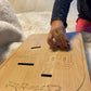 Enfant jouant avec la planche à histoire Montessori en bois ‘Les Cadeaux du Père Noël’, encastrant les pièces en forme de cadeaux dans les cheminées.