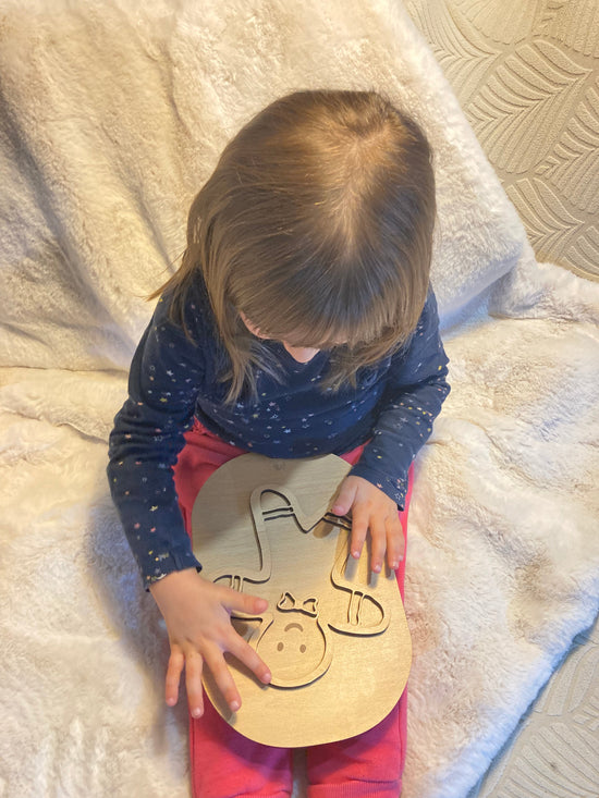 Enfant jouant avec la planche Montessori Bonhomme Pain d’Épice, développant sa coordination et sa motricité fine sur un fauteuil douillet